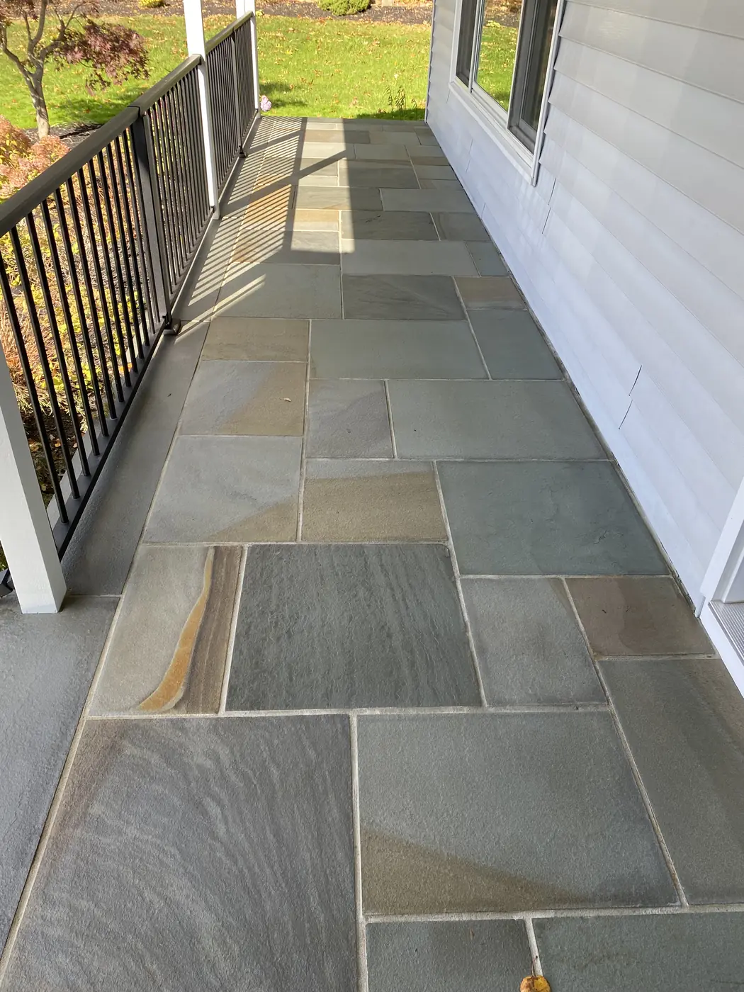 Bluestone porch floor in blue and tan tones with a black railing, cleaned in Glastonbury, CT