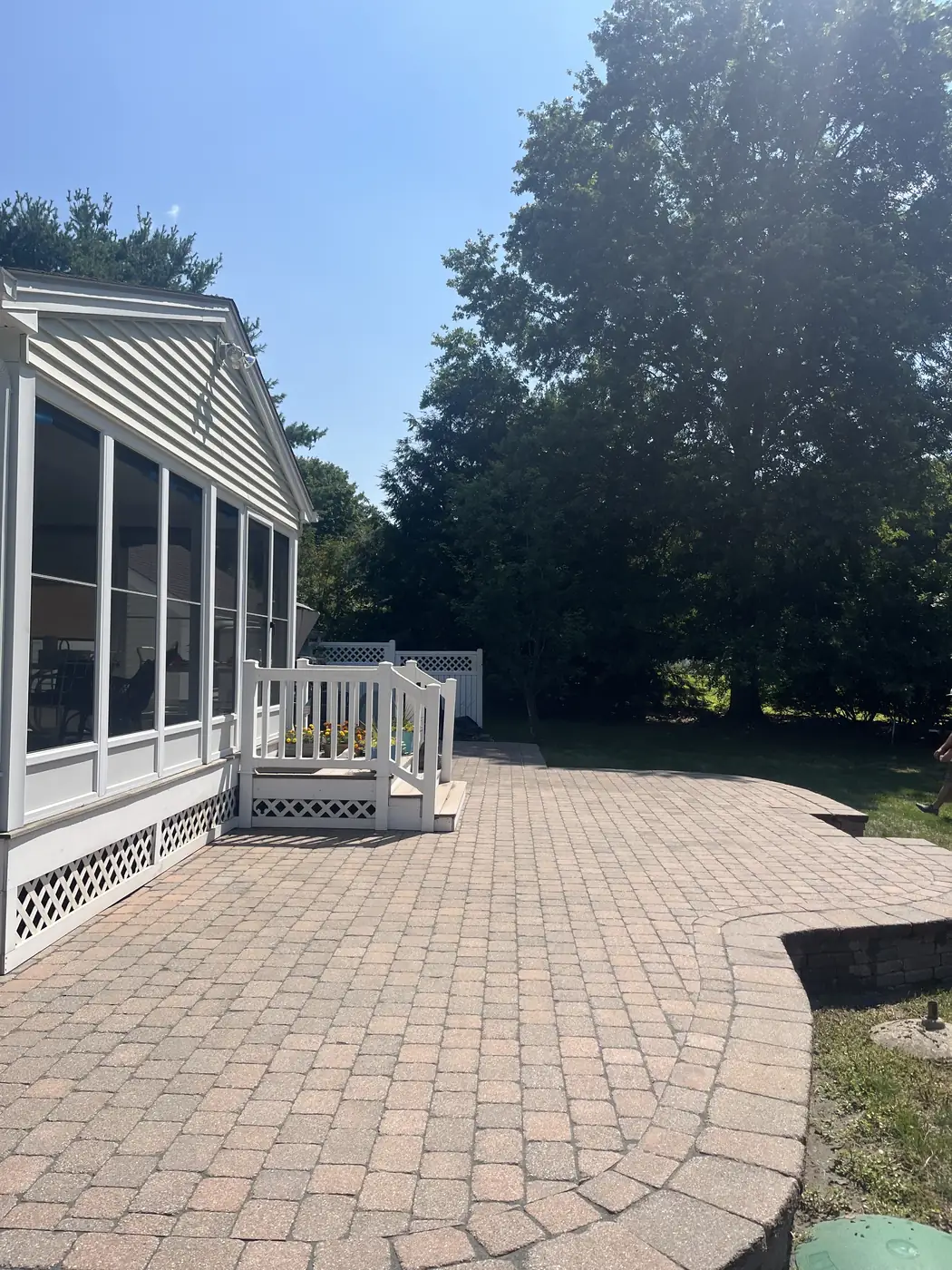 Brick-red paver patio with a rounded edge beside a screened porch in Cheshire, CT