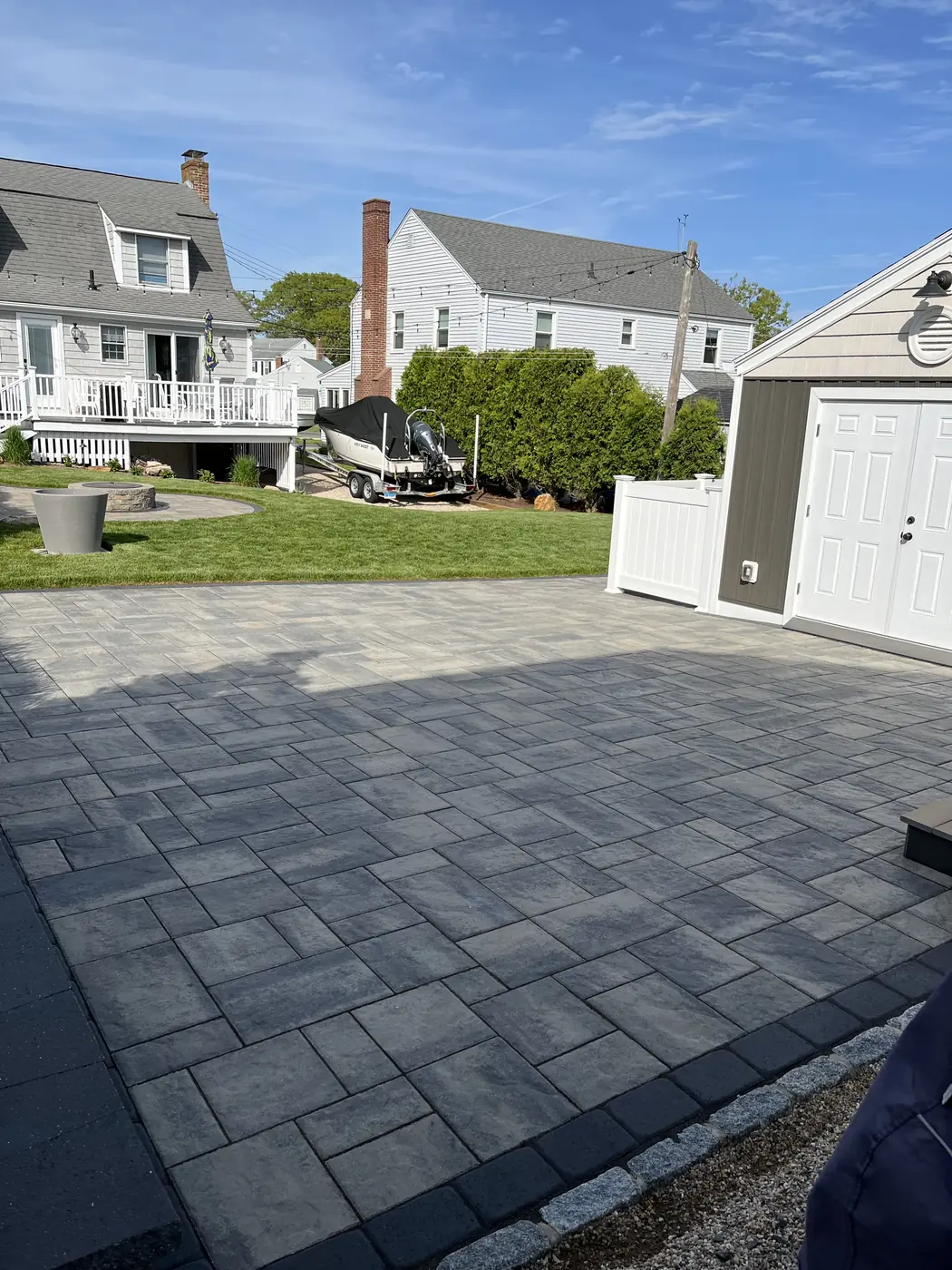 Charcoal-blend paver parking court with a granite cobble edge near a white garage in Old Lyme, CT