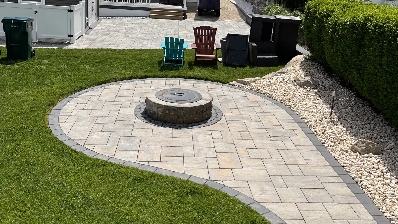 Fire pit patio and walkway Round fire pit patio with a curving paver walkway and charcoal border on a lawn in Old Lyme, CT