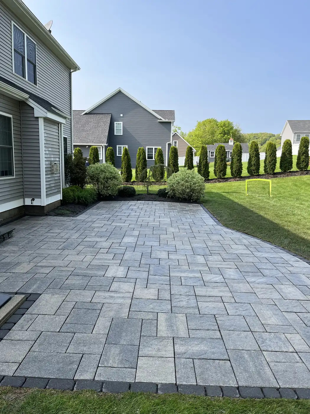 Gray patio, Southington Gray paver patio with a charcoal border behind a two-story home after sealing in Southington, CT