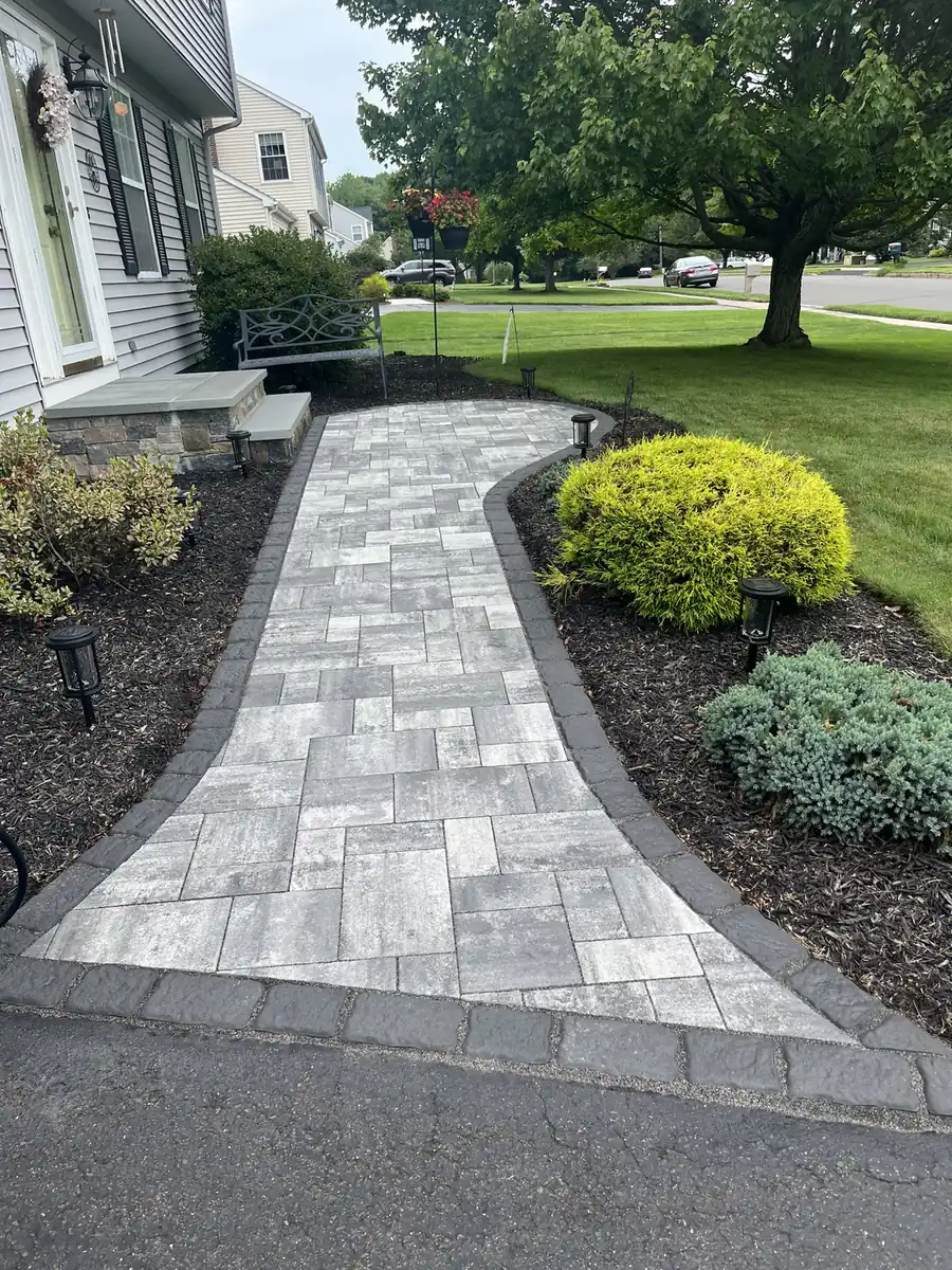 Gray paver walkway with a charcoal border curving from the driveway to front steps in Cheshire, CT