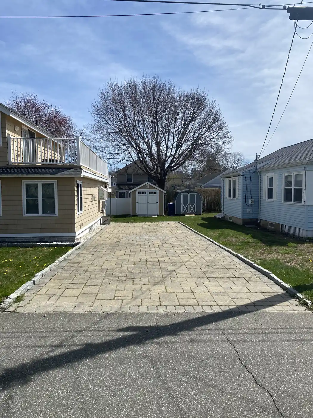 Cleaned paver driveway with a granite cobblestone curb between shoreline cottages in Old Lyme, CT
