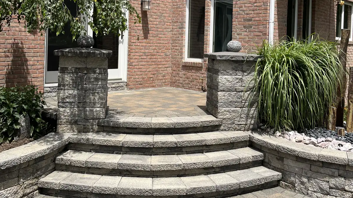 Paver patio with curved block steps and stone pillars at a brick home in Rocky Hill, CT