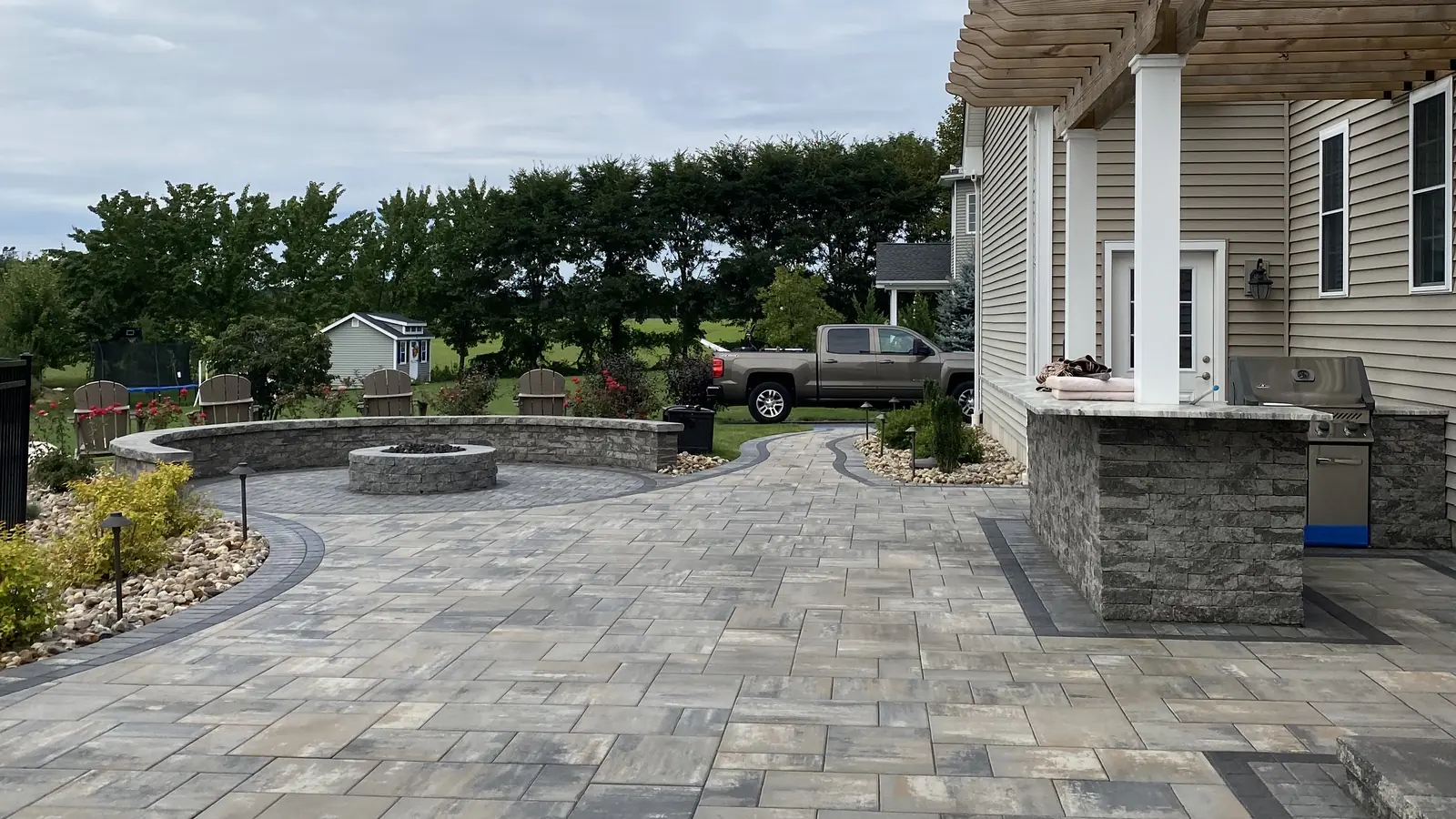Paver patio, Cromwell Large paver patio with a fire pit seat wall and stone bar under a pergola in Cromwell, CT