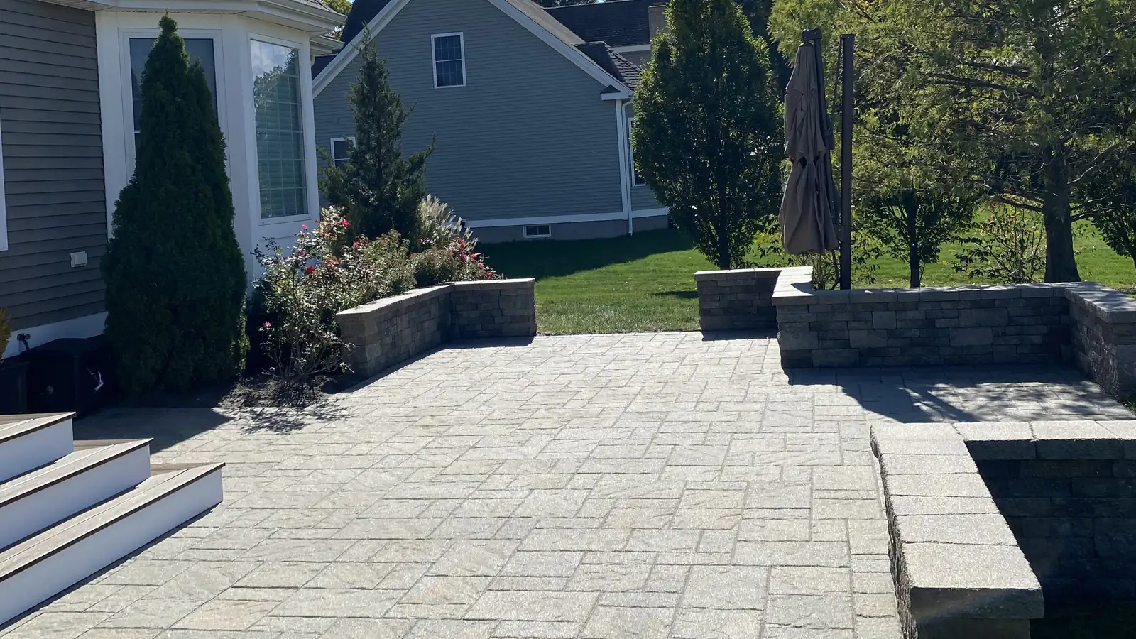 Paver patio with block seat walls and wide steps behind a home in Cromwell, CT