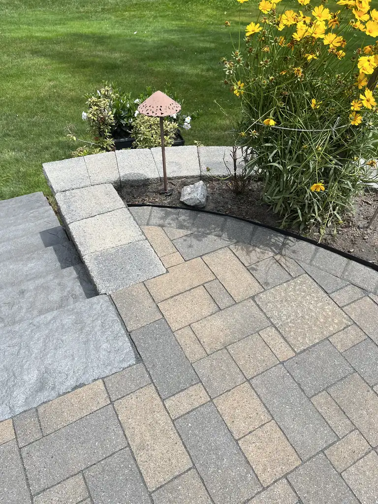 Patio wall cap detail Corner of a paver patio and block wall cap beside yellow coreopsis in Rocky Hill, CT
