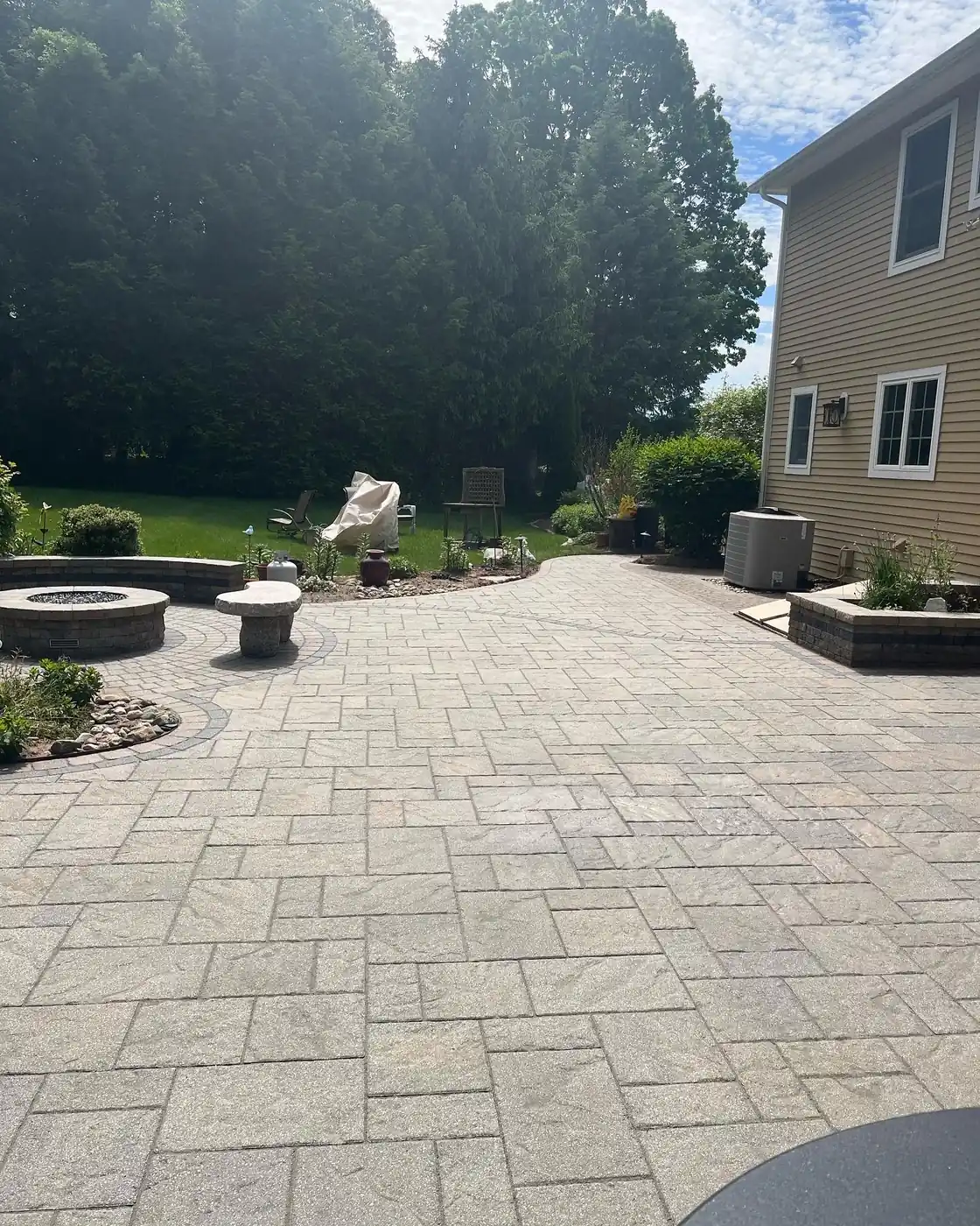Wide view of a cleaned paver patio with fire pit seating and planters in South Windsor, CT