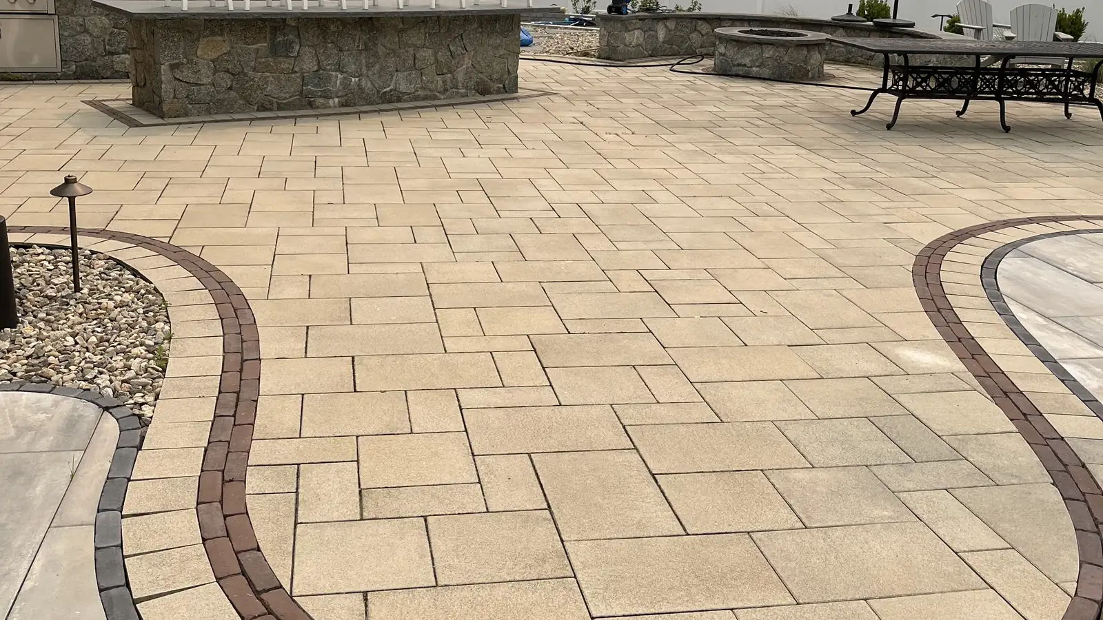 Tan paver pool patio with a red and charcoal serpentine inlay and stone bar in Avon, CT