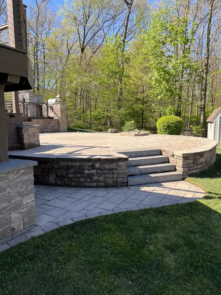 Raised patio, Plainville Raised paver patio with a curved block retaining wall and steps on a wooded lot in Plainville, CT