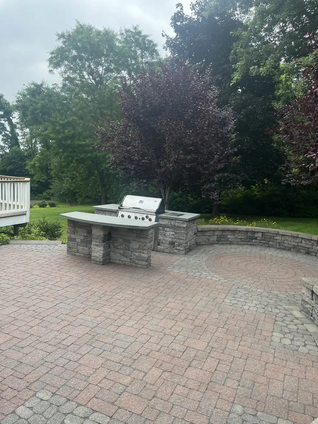 Red paver patio with a built-in stone grill station and seat wall in Middletown, CT