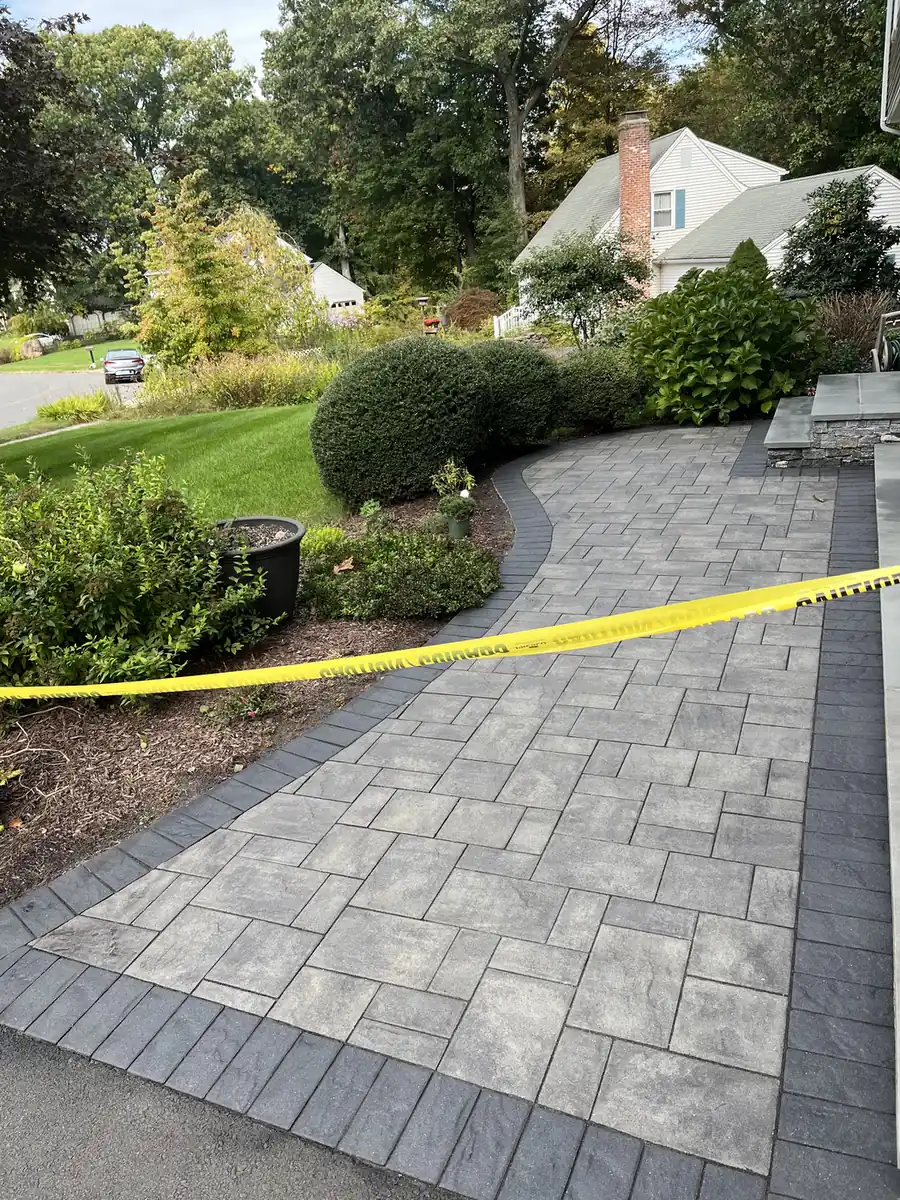 Freshly sealed gray paver walkway roped off with caution tape while it cures in Cheshire, CT