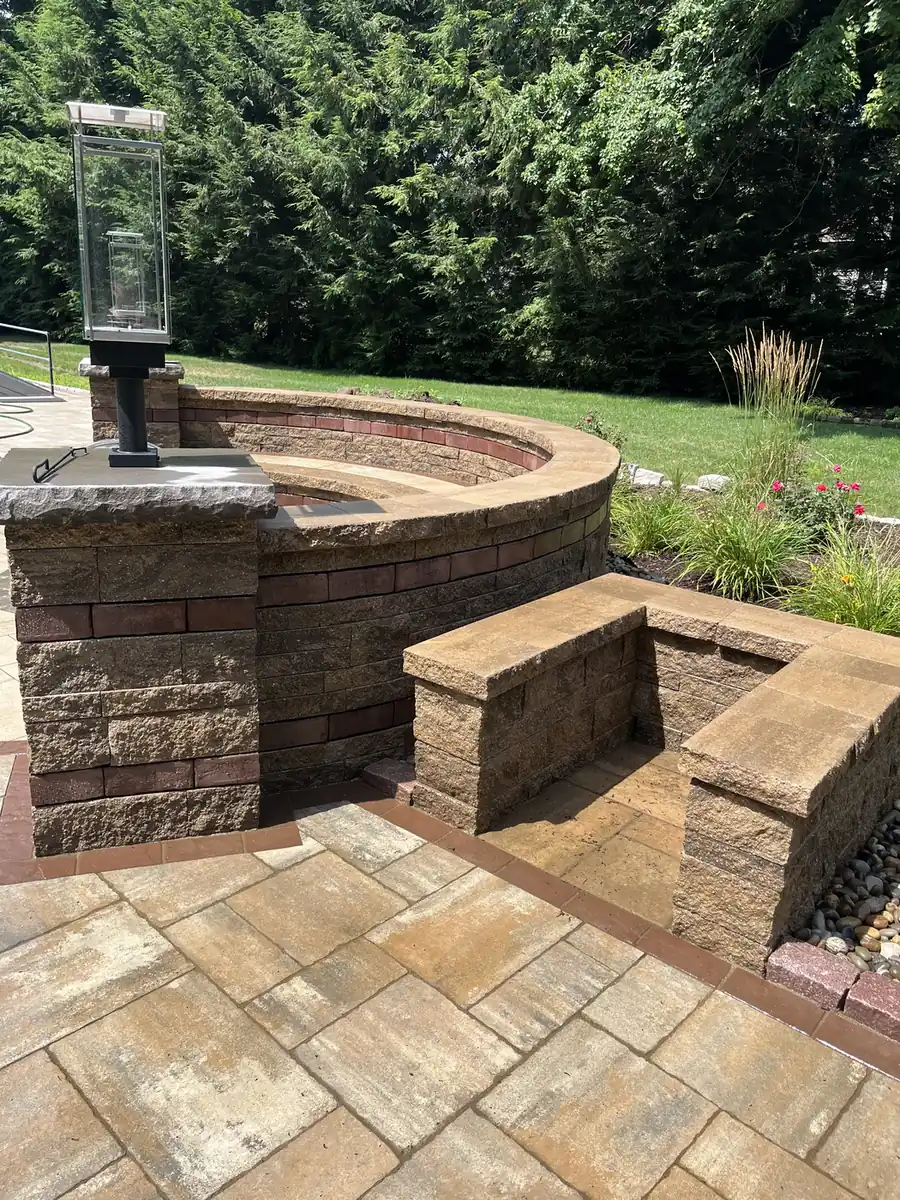 Curved block seat wall and lamp pillar on a sealed paver patio with a dark border in Bristol, CT