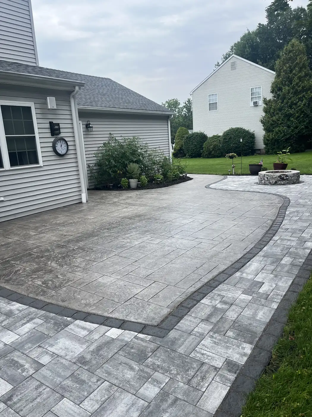 Sealed stamped concrete patio with a charcoal paver border and fire pit in Cheshire, CT